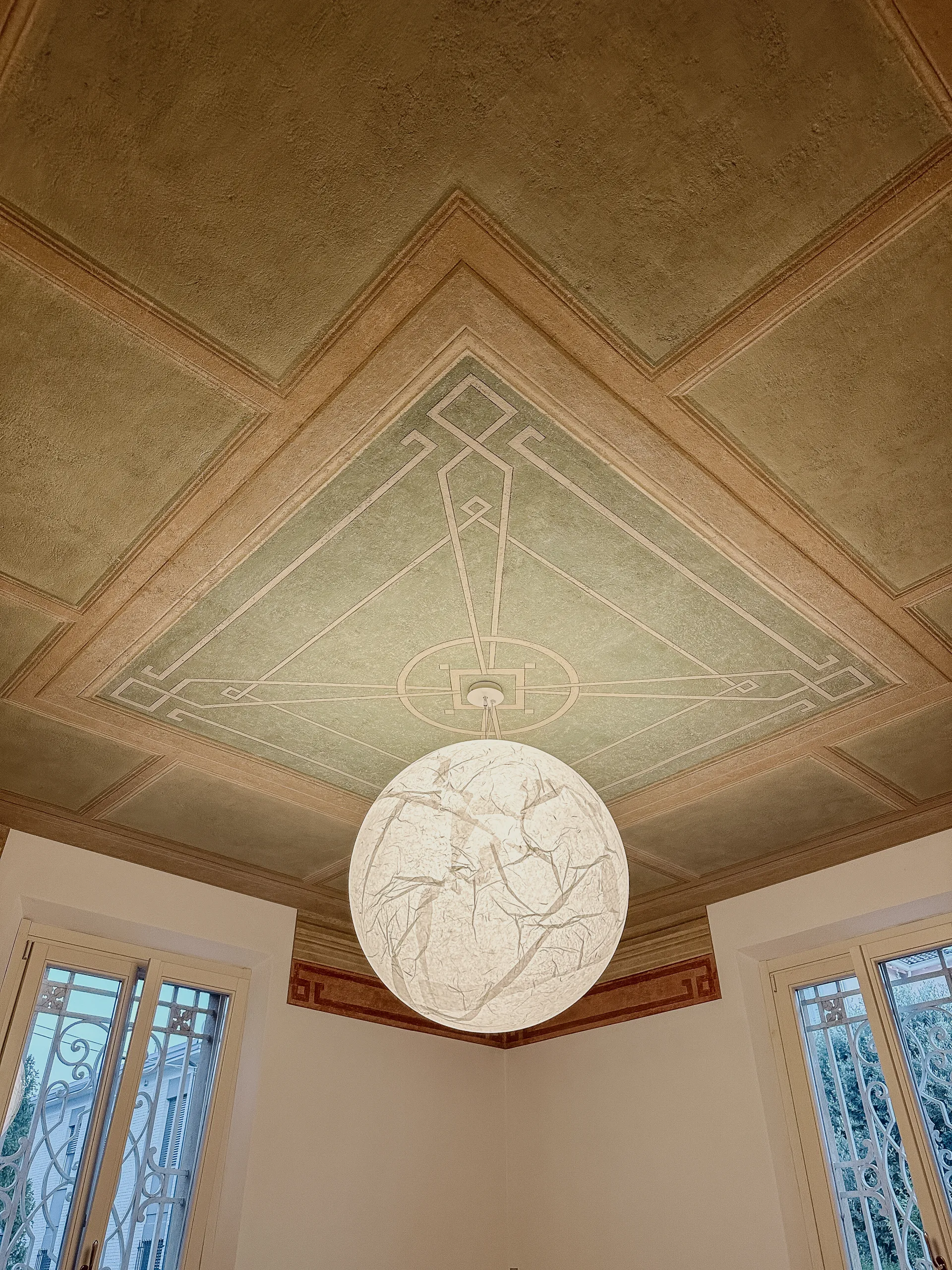 Una lampada sferica in carta sotto il soffitto affrescato di Villa N